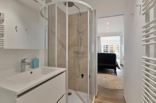 a white bathroom with a shower and a sink at Appartement San Marino 4B in Middelkerke