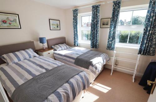 a bedroom with two beds and two windows at 28 Anchorage Way in East Cowes