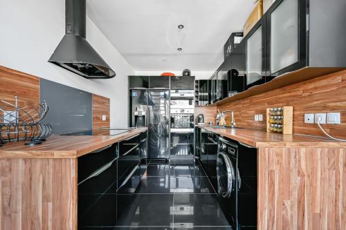 une grande cuisine avec des appareils noirs et des comptoirs en bois dans l'établissement Le Loft - 8p - Balcon - Salle de Sport - Parking, à Pantin