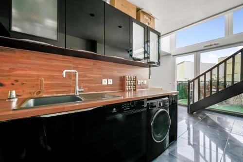 une cuisine avec un évier et une machine à laver dans l'établissement Le Loft - 8p - Balcon - Salle de Sport - Parking, à Pantin