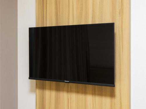 a flat screen tv hanging on a wooden wall at Kyoto Plaza Hotel Kintetsu Jujo in Kyoto
