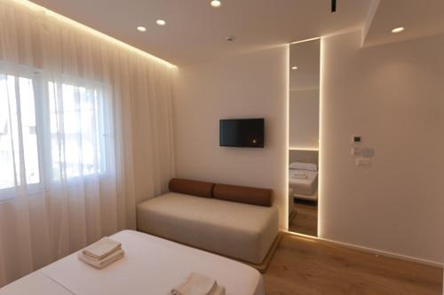 a bedroom with a couch and a tv on a wall at Villa Mucho in Sarandë