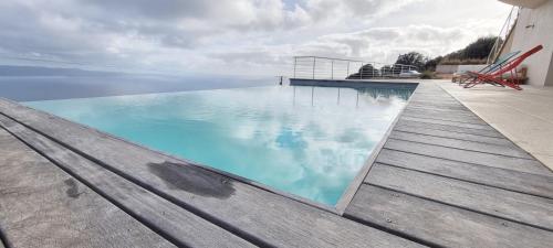 una piscina de agua azul y una terraza de madera en Villa de standing piscine chauffée vue mer Corse du sud, en Coti-Chiavari