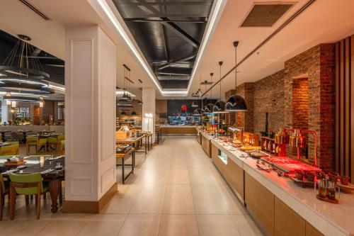 ein Restaurant mit einem langen Korridor, an dem Tische und Stühle stehen in der Unterkunft Holiday Inn Ankara - Cukurambar by IHG in Ankara