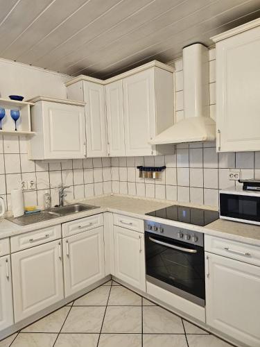 a kitchen with white cabinets and a stove top oven at Haus Mit Garten in Nürnberg