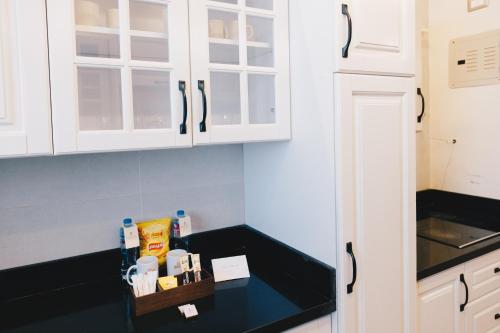 a kitchen with white cabinets and a black counter top at The Suites near AUC by Elegant Hospitality in Cairo