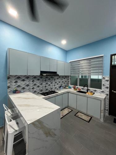 a kitchen with white cabinets and a blue wall at Roza Homestay in Kampong Parit Gantong