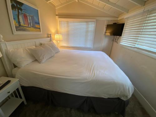 a bedroom with a large white bed with a window at Carmel Dolores Cottages in Carmel