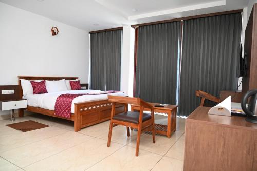 a bedroom with a bed and a chair and a desk at Hotel Aamis Villa in Pulpally