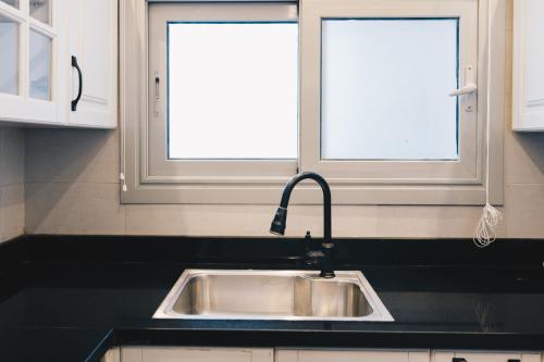 a kitchen with a sink and two windows at The Suites near AUC by Elegant Hospitality in Cairo
