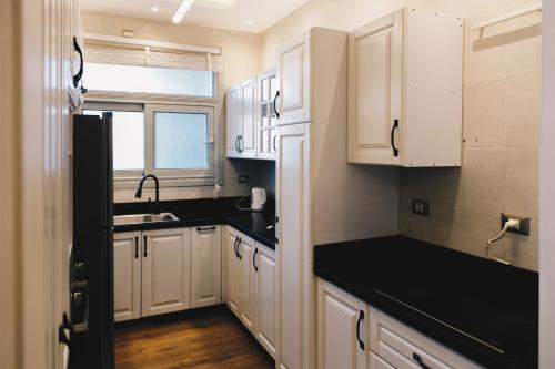a kitchen with white cabinets and a sink and a window at The Suites near AUC by Elegant Hospitality in Cairo