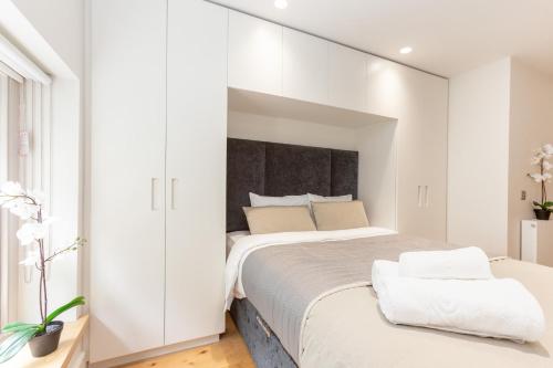 a bedroom with a large bed with white walls at BnBNova - 2BR 2BA in Fitzrovia & Soho in London