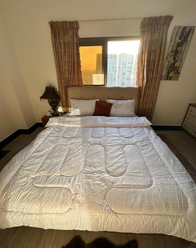 a large white bed in a bedroom with a window at Entire 1-Bedroom Apartment with Balcony, Sharjah in Sharjah