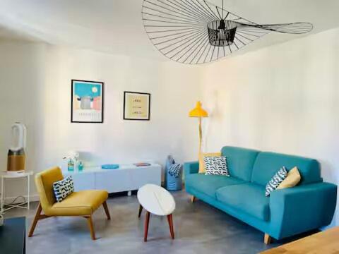 un salon avec un canapé bleu et un fauteuil jaune dans l'établissement Appartement lumineux Côte des Basques, à Biarritz