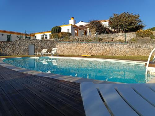 a swimming pool with chairs and a house at Casal Serrano Charme e Tranquilidade in Reguengo Grande