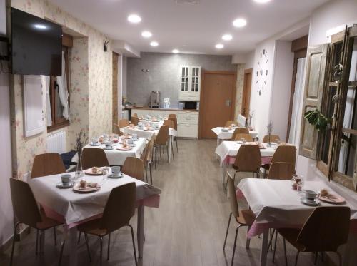 a restaurant with white tables and chairs and a kitchen at La Casa de los Soportales in Mansilla de las Mulas