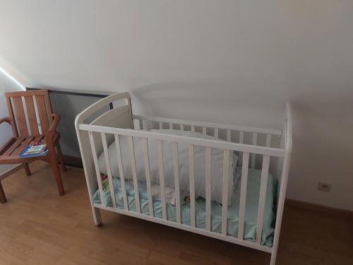 a white crib in a room with a chair at Nivekerke 8 Nieuwmunster De Haan, 3-bedroom holiday house for 4 to 6 people, between Wenduine, 1 km, and De Haan, 2 km, 500 meters from the beach,15 min from Bruges, Ostend and Knokke, nice big fenced garden in Zuienkerke