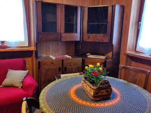 una stanza con un tavolo con un vaso di fiori sopra di La cuccia di Elfo a Prali