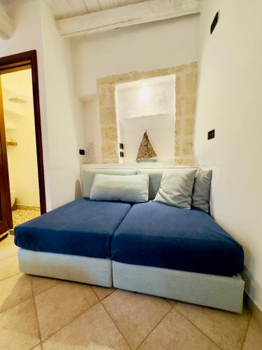 a blue bed in a white room with a mirror at Amoredimare Casa Vacanze in Polignano a Mare