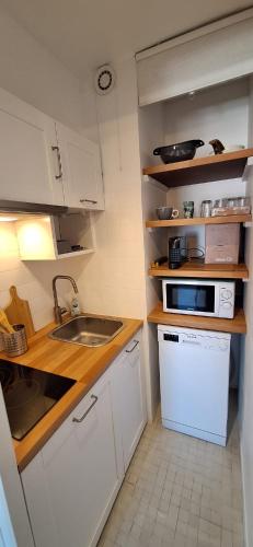 une petite cuisine avec un évier et un micro-ondes dans l'établissement L escale, à Saint-Martin-de-Ré