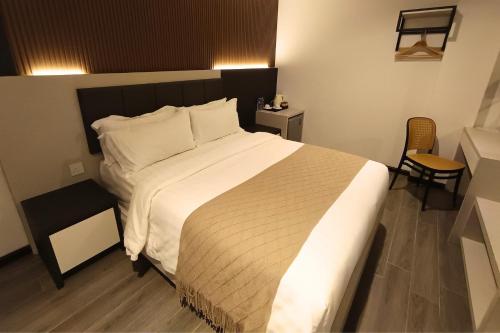 a bedroom with a large bed with white sheets and pillows at De Quinton Hotel in Ipoh