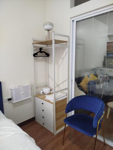 a bedroom with a blue chair and a dresser at The Orabella 27F Chill Zone with a View in Manila