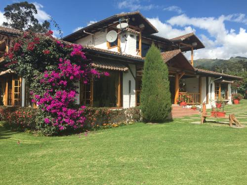 a house with purple flowers on the side of it at Casa d'Campo Tababela Hotel Boutique in Tababela