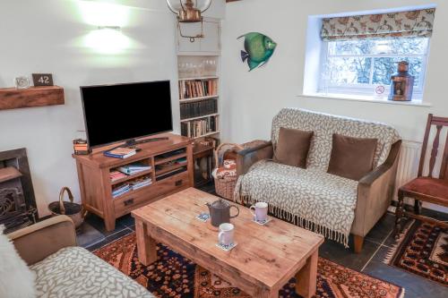 a living room with a tv and a couch and a table at Naunton Cottage in Lyme Regis