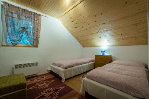 two beds in a room with a wooden ceiling at Apartmán Milka in Demanovska Dolina