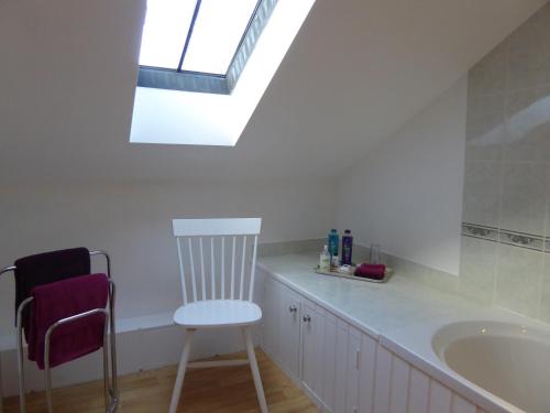 a bathroom with a chair and a sink and a skylight at Orchard House Bed and Breakfast in Grassington
