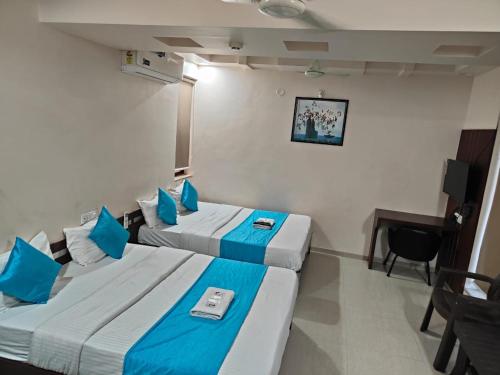 una camera d'albergo con due letti e una scrivania di Hotel Raviraj Palace a Rajkot