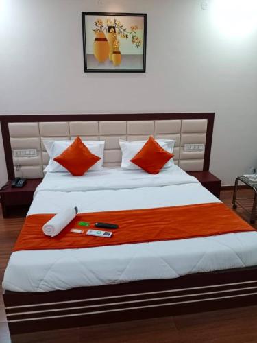 a bedroom with a large bed with orange pillows at Hotel Raviraj Palace in Rajkot