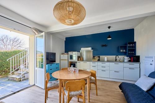a kitchen with a table and chairs in a room at La Parenthèse Normande - Proche Plage in Saint-Aubin-sur-Mer