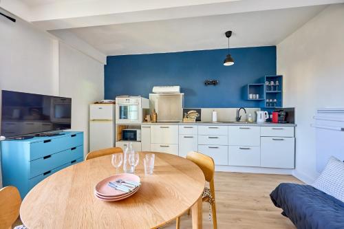 a kitchen with a wooden table and a blue wall at La Parenthèse Normande - Proche Plage in Saint-Aubin-sur-Mer
