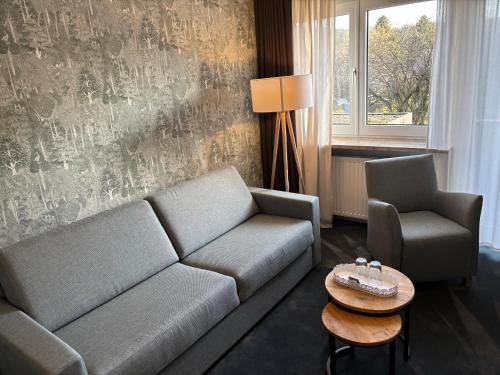 a living room with a couch and a chair and a table at Hotel Haus am Hochwald in Hahnenklee-Bockswiese