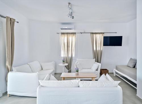 a white living room with white couches and a table at Opal Apartment in Prodromos Paros