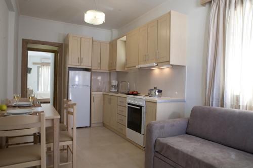 a kitchen with white cabinets and a couch and a table at Savinos Rooms in Vasiliki