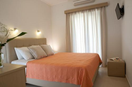 a bedroom with a bed with an orange blanket and a window at Savinos Rooms in Vasiliki