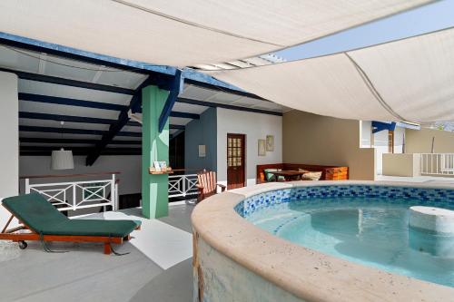 a large swimming pool with a green chair and an umbrella at The Ritz Village in Willemstad