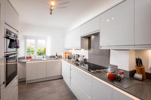 a white kitchen with white cabinets and appliances at Rosegate House, Elterwater in Elterwater