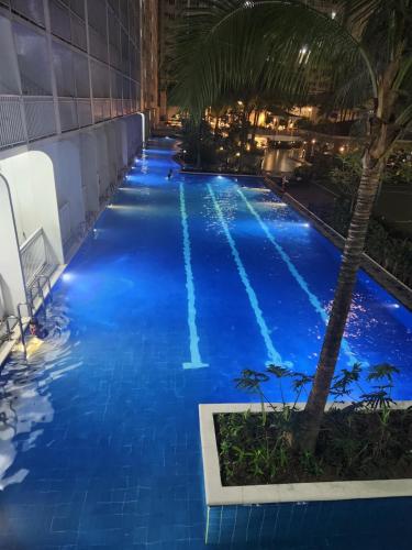 ein Pool in der Nacht mit blauem Wasser und einer Palme in der Unterkunft Shore residences tower D Staycation near Sm moa in Manila