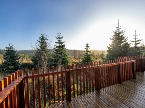 a wooden deck with a fence and some trees at Garwnant, Brecon Beacons Cabins - Forest Holidays in Dol-y-gaer Station