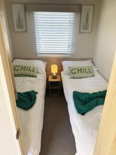 two beds in a small room with a window at Meadowside Caravan Hire Haven Kent Coast in Allhallows