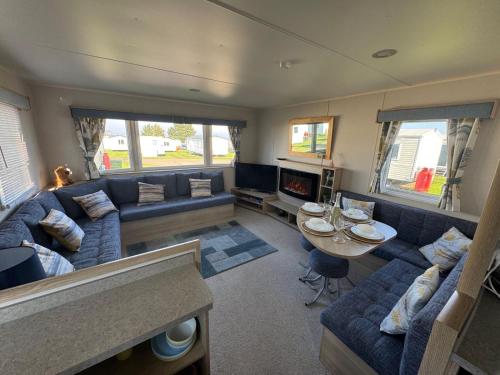 a living room with a blue couch and a table at Meadowside Caravan Hire Haven Kent Coast in Allhallows