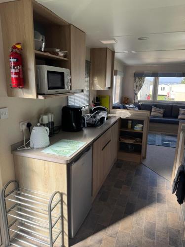 a kitchen with a counter top and a microwave at Meadowside Caravan Hire Haven Kent Coast in Allhallows