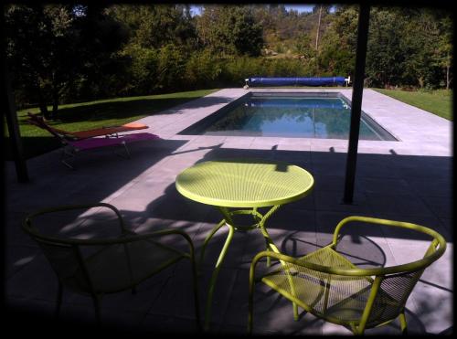 une table et des chaises jaunes à côté de la piscine dans l'établissement Nid en Garrigue, à Lauret