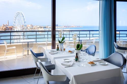 a restaurant with tables and chairs and a view of the ocean at JR Hotels Bari Grande Albergo delle Nazioni in Bari