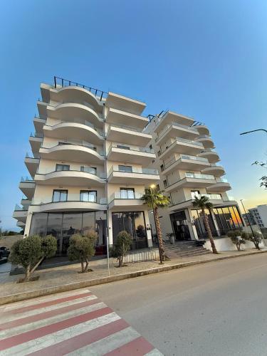 un grand bâtiment blanc avec des palmiers devant dans l'établissement Day Lux Premium Apartments, à Saranda