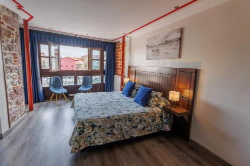a bedroom with a bed with blue pillows at Hotel Puerto Rico in Llanes