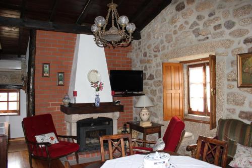 a living room with a fireplace and a tv at Casa do Balcao in Castelo Novo